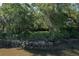Picturesque view of a home nestled among trees with waterfront access and natural rock seawall at 2180 Wappoo Hall Rd, Charleston, SC 29412