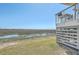 Back of coastal home with marsh views from the balconies, surrounded by grass and waterway at 221 E Mariners Cay # 221, Folly Beach, SC 29439