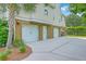 Long driveway featuring multiple garage doors, a side door, and lush landscaping around the base at 2269 Hartfords Bluff Cir, Mount Pleasant, SC 29466