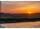 Water view showcasing a serene sunset over the river and expansive marshland in the horizon at 27 Rebellion Rd, Charleston, SC 29407