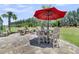 Outdoor patio featuring an umbrella-covered dining table, fire pit, and a meticulously manicured lawn at 467 Hidden Meadow Ln, Summerville, SC 29486