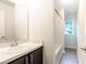 Bathroom features a dark vanity, white sink, mirror, white walls, and a shower-tub combo at 5001 Hay Bale Ct, Summerville, SC 29485