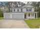New two-story home boasts white siding, dark shutters, and a spacious three-car garage in a wooded area at 5182 Stono Plantation Rd Dr, Hollywood, SC 29449