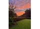 Beautiful backyard with lush greenery, bird bath, manicured landscaping, and vibrant sunset at 525 Scholar Way, Summerville, SC 29486