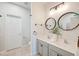 Bright bathroom featuring double sinks, two mirrors, light-colored cabinets, and a white door at 543 Mclernon Trce, Johns Island, SC 29455