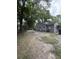 View of backyard with trees and gravel, showing the exterior of the gray, single-story home at 715 Yew St, Charleston, SC 29407