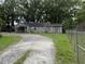 A single-story home with a circular gravel driveway surrounded by lush greenery and a chain link fence at 715 Yew St, Charleston, SC 29407