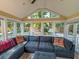Spacious sunroom with ample natural light, a large comfortable sectional sofa, decorative pillows, and views of the backyard at 946 Law Ln, Mount Pleasant, SC 29464