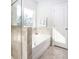 Bright bathroom featuring a soaking tub with stone surround, large window, and tiled floors at 1034 Scotch Bonnet Way, Summerville, SC 29485
