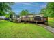 A backyard featuring a well-maintained lawn, wooden deck, and mature trees providing shade and privacy at 204 Pete Ewers Dr, Summerville, SC 29483