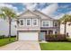 Two-story home with stone and siding accents, light blue door, palm trees, and an attached garage at 228 Donatella Dr, Goose Creek, SC 29445
