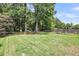 Large backyard with green grass and mature trees around a firepit sitting area at 3061 Penny Ln, Johns Island, SC 29455