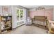 Bedroom with pink accent wall, crib, and bookcase at 3061 Penny Ln, Johns Island, SC 29455