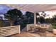 A cozy outdoor dining area under a pergola with comfortable seating and a scenic view of the backyard at 3307 Waterway Blvd, Isle of Palms, SC 29451