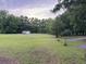 Picture of a grassy vacant lot with a small shed and lush trees against a cloudy skyline at 351 Duncan Chapel Rd, Harleyville, SC 29448