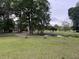 Scenic pond reflecting the sky, surrounded by lush trees and well-maintained green grass at 351 Duncan Chapel Rd, Harleyville, SC 29448