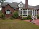 Rear exterior view featuring a sun room, brick facade, and manicured landscaping at 351 Duncan Chapel Rd, Harleyville, SC 29448