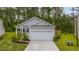 A cozy gray home boasts a one-car garage, complemented by lush landscaping against a backdrop of towering trees at 444 Cedarview Rd, Summerville, SC 29486