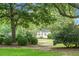 Landscaped front yard with large trees and trimmed bushes, offering a view of a quaint home at 4810 Parkside Dr, North Charleston, SC 29405