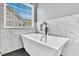 Modern white soaking tub with black plumbing fixtures, next to a window with blinds, and gray marble-like tiling at 5257 Mulholland Dr, Summerville, SC 29485