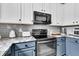 Close-up of a well-equipped kitchen featuring modern appliances, marble countertops, and stylish blue lower cabinets at 5257 Mulholland Dr, Summerville, SC 29485