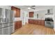 Well-lit kitchen with stainless steel appliances, brown wood cabinets, and light wood flooring at 5375 Highway 174, Adams Run, SC 29426