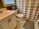 Compact bathroom features a toilet, shower with curtain, neutral tiles and finishes at 7 Lavington Rd, Charleston, SC 29407