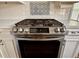 Modern stainless steel gas range with a black oven, white cabinets, and decorative backsplash tiles at 7 Lavington Rd, Charleston, SC 29407