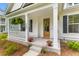Inviting front porch with white columns, potted flowers, and a wooden door with glass wreath at 727 Hodge Rd, Summerville, SC 29483