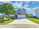 Charming two-story home features a driveway, lush lawn, mature tree and a blue front door at 8038 Regency Elm Dr, North Charleston, SC 29406