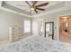 Relaxing bedroom with neutral decor, tray ceiling, ceiling fan, and a doorway to the en suite bathroom at 8038 Regency Elm Dr, North Charleston, SC 29406
