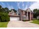 Charming two-story brick home featuring a two-car garage, red shutters, and beautiful landscaping at 8522 Long Meadow Dr, Charleston, SC 29420