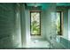 A luxurious bathroom featuring a soaking tub, a large window showcasing outdoor greenery, and stylish, light green tile at 905 Palm Blvd, Isle of Palms, SC 29451