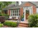 Close-up of brick home featuring a cozy front porch with seating and meticulous landscaping at 95 Gordon St, Charleston, SC 29403