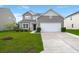 Two-story home features manicured lawn, neutral siding, stone accents, and attached two-car garage at 9711 Tackle St, Ladson, SC 29456