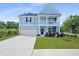 Charming two-story home featuring a light blue facade, inviting front porch, and well-manicured lawn at 1004 Saltwater Cir, Johns Island, SC 29455