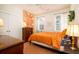 Cozy bedroom with an orange floral bedspread, hardwood floors and large windows with curtains at 1076 Hatfield St, North Charleston, SC 29405