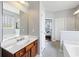 Bright bathroom featuring wood vanity, soaking tub, a large mirror, neutral walls, and easy access to the bedroom at 1470 Ashley Gardens Blvd, Charleston, SC 29414