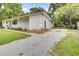 View of the home's exterior featuring light gray siding, a gravel driveway, rocking chairs and a fenced in yard at 1515 Mulberry St, Charleston, SC 29407