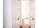 Bright hallway with multiple doors and dark hardwood floors that opens into a bright, white bathroom at 1566 Lindsey Creek Dr, Mount Pleasant, SC 29466