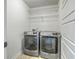 Convenient laundry room featuring modern, stainless-steel washer and dryer set with overhead shelving at 211 Saxony Loop, Summerville, SC 29486