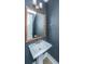 A powder room with pedestal sink, chrome fixtures, dark blue walls and wood-look floors at 2402 Brackish Dr, Mount Pleasant, SC 29466