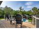 Outdoor deck features seating overlooking a sparkling pool and manicured lawn surrounded by lush greenery at 4121 Golf Cottage Ln, Johns Island, SC 29455