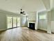 Comfortable living room with a fireplace, ceiling fan, wood floors, and sliding glass doors to the backyard at 5702 Barbary Coast Rd, Hollywood, SC 29449