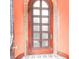 Arched wooden door featuring vintage textured glass panes, set against a warm, inviting orange wall at 81 Rutledge Ave, Charleston, SC 29401