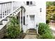 Quaint entryway featuring a white door and staircase, surrounded by vibrant greenery at 81 Rutledge Ave, Charleston, SC 29401