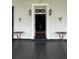 Inviting entrance with a white door framed by wall-mounted lanterns and iron accent tables at 81 Rutledge Ave, Charleston, SC 29401