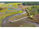 Aerial view of winding river with dock and structure, surrounded by lush landscapes offering serenity and privacy at 840 Forrest Dr, Charleston, SC 29492
