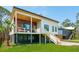 Modern home with unique architecture, featuring elevated design, wood accents, and a lush green lawn at 1012 E Erie Ave, Folly Beach, SC 29439