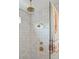 Close-up of a shower with brass fixtures and a tiled wall; a patterned towel hangs nearby at 1012 E Erie Ave, Folly Beach, SC 29439